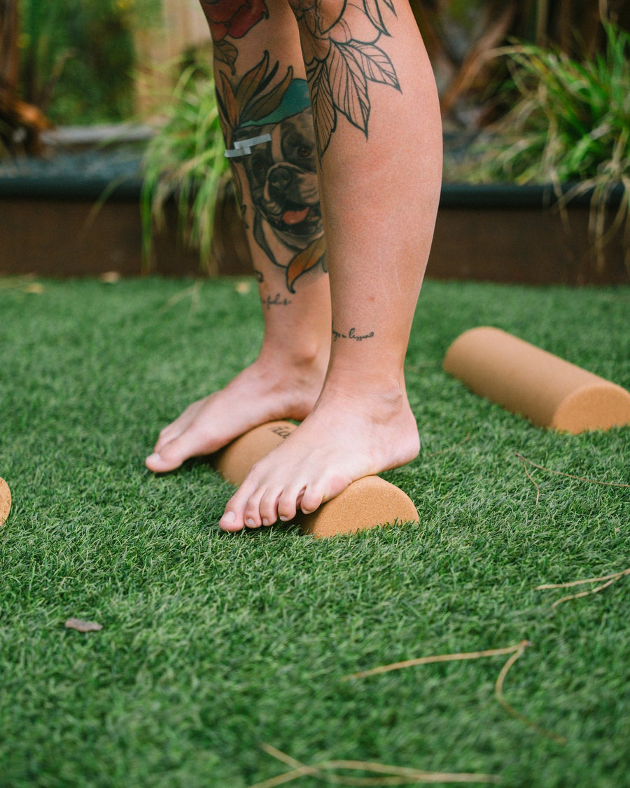 Bare feet standing on The Nude Foot cork foam rollers for post-WOD foot recovery, balance and mobility