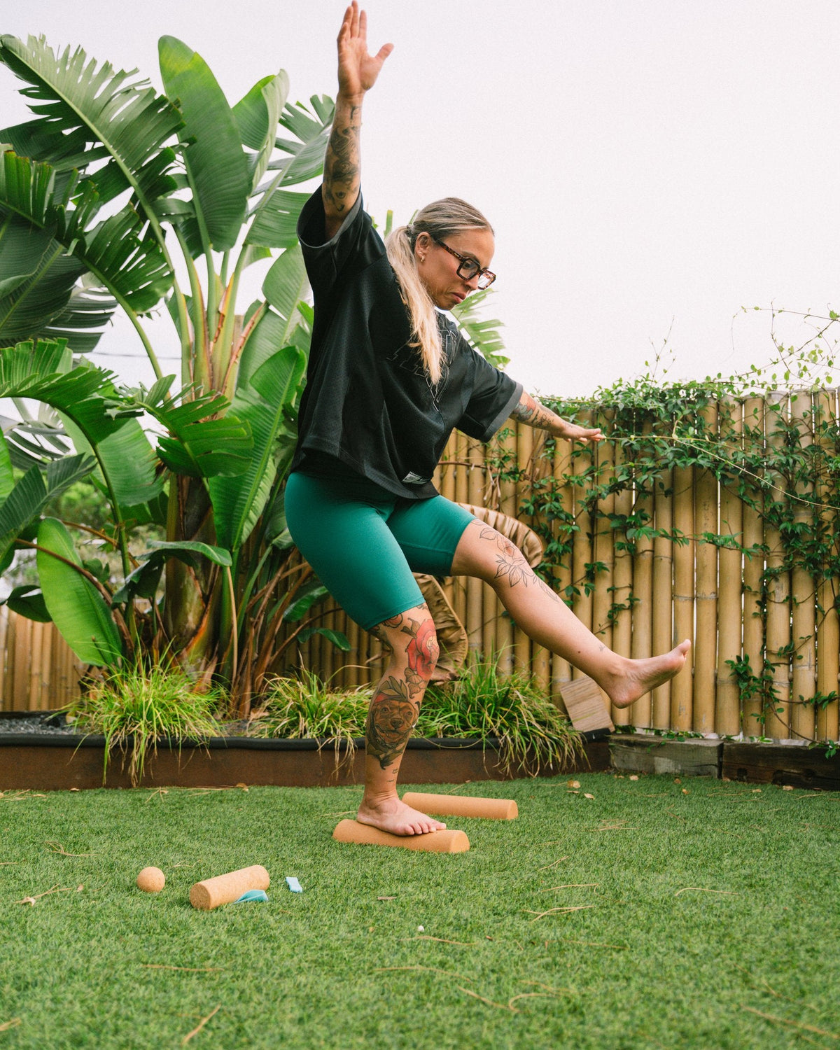Woman doing a barefoot balance exercise on The Nude Foot cork rollers as part of a foot mobility routine