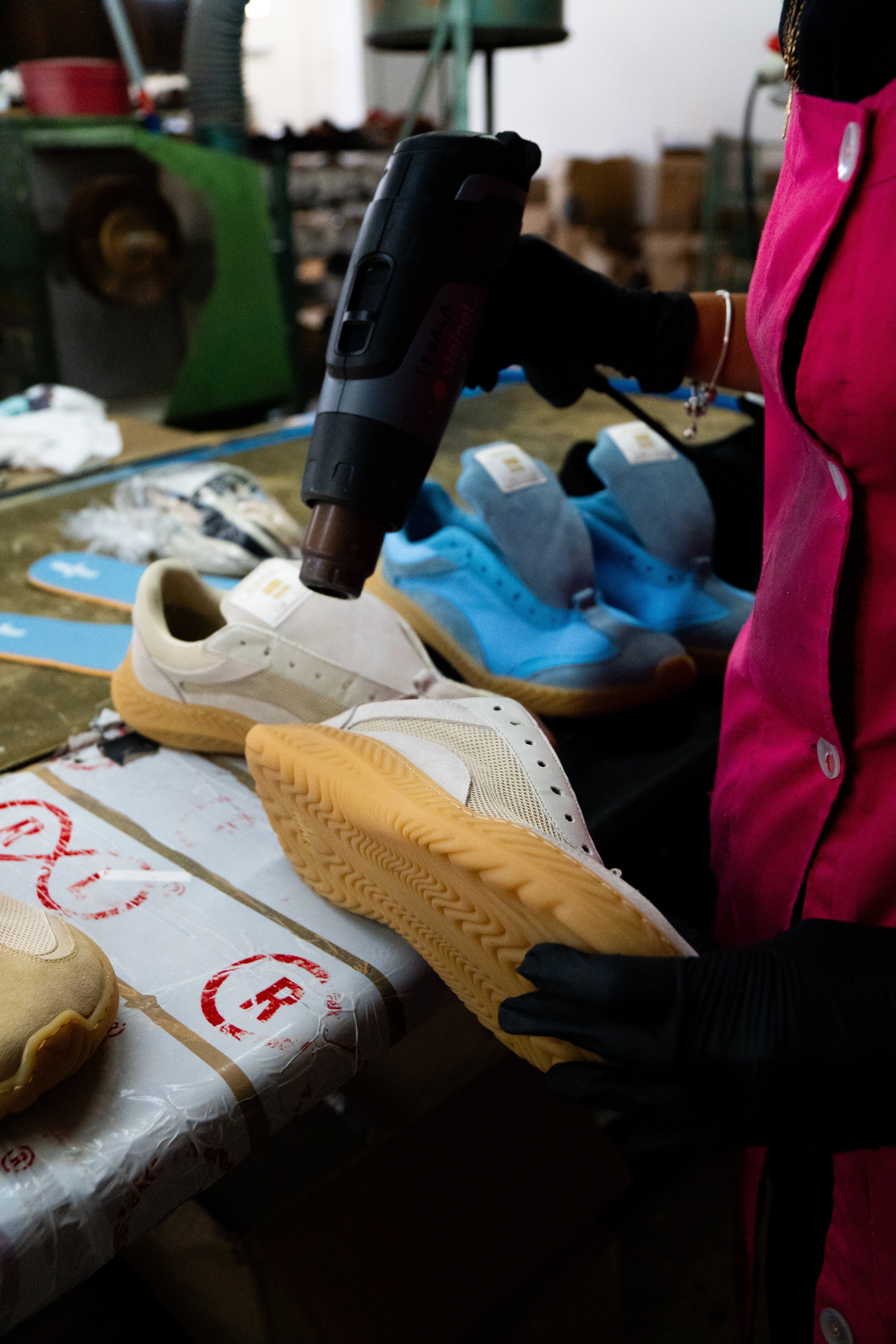 Person working on a sneaker with a heat gun in a workshop setting